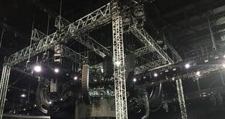Ground Support aus Traversentürmen mit abgehängten Lautsprechern und Scheinwerfern in einer leeren Arena.